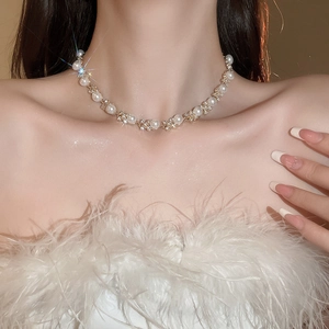Primo piano di una collana di fiori con diamanti e perle sul collo di una modella