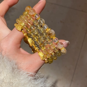 Macro shot of citrine quartz beads with gold filigree charms on handmade bracelets