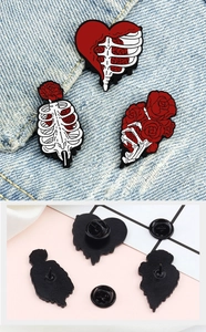 Front and back view of cartoon skull heart and rose enamel pins on blue denim fabric