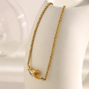 Close-up of 18K gold plated necklace with teardrop zircon and pearl on a white stand