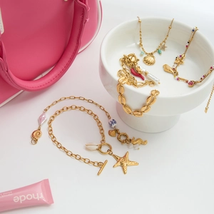 Detail of 18K gold stainless steel bracelet with seashells and starfish charms