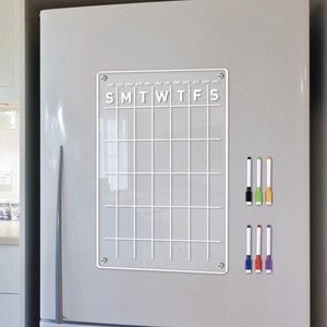Macro shot of magnetic acrylic monthly calendar with six dry erase markers on a fridge