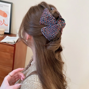 Détail de la pince à cheveux en tweed montrant la texture du tissu multicolore en coiffure
