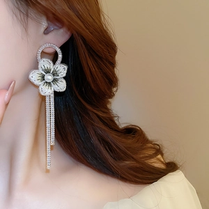 Détail de boucles d'oreilles fleuries à franges avec broderies, perles et strass