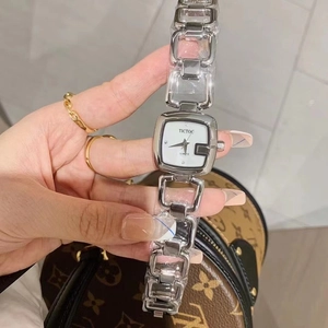 Detail shot of a silver square face watch with a chain bracelet against a patterned bag