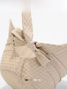 Detail of beige bucket hat showing bubble texture fabric and large rear bow decoration