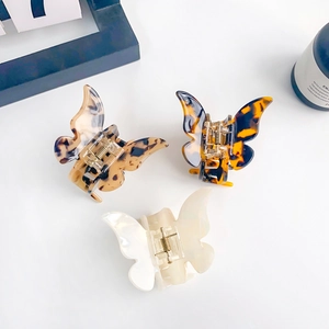 Three elegant acetate butterfly hair claws in tortoiseshell and ivory white on white