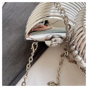 Detail of silver shell clutch bag with mirror finish and elegant wavy ribbed texture