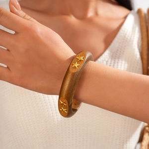 Detailed view of wide dark wood bangle featuring embedded gold star-shaped metal rivets