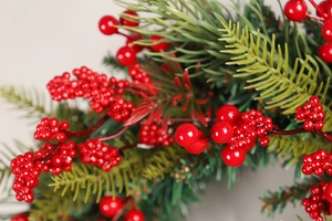 Close-up of festive Christmas wreath featuring vivid red berries and green pine needles