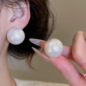 Close-up of oversized 18mm white pearl stud earrings on model for elegant style