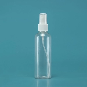 Macro shot of transparent travel spray bottle with a white pump and clear protective cap