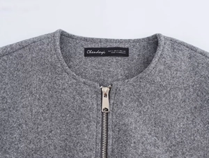 Detailed macro view of the silver zipper and grey wool felt fabric on women's jacket