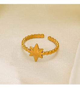 Dettaglio anello stella dorato regolabile con bordo perlato su fondo beige