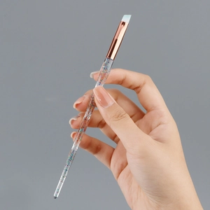 Detail of angled brow brush with glittery crystal handle and blue gradient bristles
