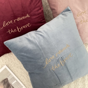 Close-up of velvet cushion covers with golden embroidery text on plush background