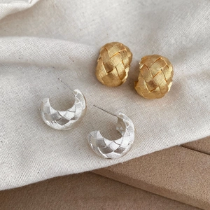 Minimalist C-shaped braided texture earrings in gold and silver finishes on fabric