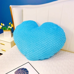 Vue détaillée du coussin en peluche bleu en forme de cœur avec tissu plissé doux