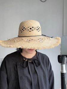 Detail of hollow diamond weave pattern and raw fringe edges on a wide brim straw hat