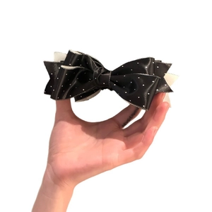 Elegant black satin hair clip with white polka dots featuring a layered bow design