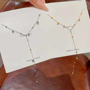 Close-up of gold and silver Y-shaped tassel necklaces with delicate metallic beads