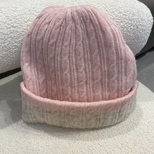 Close-up of pink and beige wool blend knit beanie with chunky cable texture and soft finish