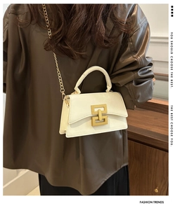 Detail view of a white faux leather handbag with gold chain strap and square buckle clasp