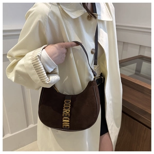 Détail du lettrage en métal doré sur le sac hobo en daim marron avec fine bandoulière