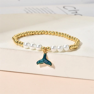 Detail of beaded bracelet with gold beads, white pearls and blue fishtail charm on stairs