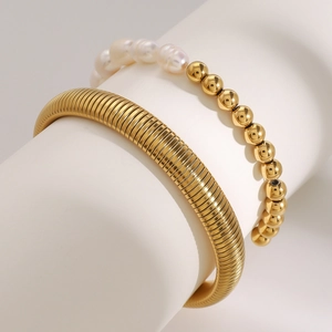 Dettaglio del set bracciale rigido a serpente placcato oro 18k e perle bianche