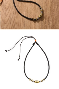 Macro detail of braided black faux leather cord with gold and silver soccer ball metal beads