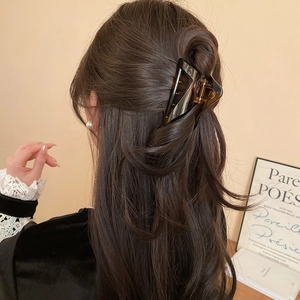 Detail view of large amber triangular hair claw clip worn on thick hair for elegant styling