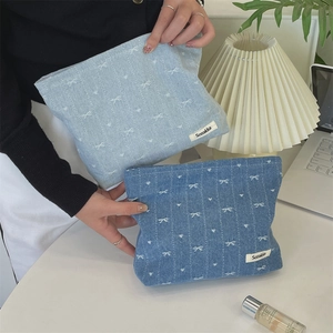 Detail of denim cosmetic bags with white bow patterns and branded Sozakka label