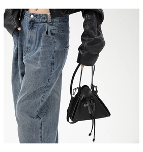 Detail of gothic triangle leather handbag featuring metallic cross and drawstring closure