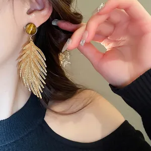 Elegant gold leaf earrings with tiger eye stone on model showing luxury forest style