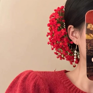 Dettaglio del pettine per capelli con fiori rossi e orecchini di perle abbinati su modella