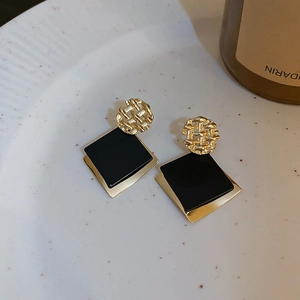 Detailaufnahme retro goldene Metallstecker mit schwarzen quadratischen Harz-Anhängern