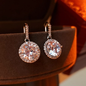 Macro shot of silver zircon hoop earrings with halo design on dark velvet background