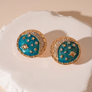 Detailed close-up of blue enamel celestial earrings with stars and saturn on stones