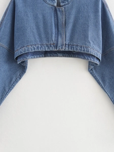Detail view showing stitching and seams on blue denim cropped jacket sleeve and hem