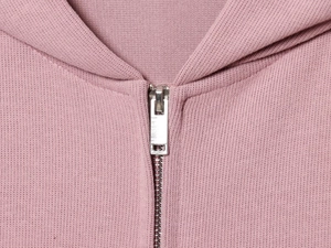 Détail d'un sweat à capuche rose tricoté avec fermeture éclair en argent et texture douce