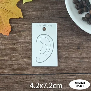 Close-up of a white paper earring card with New Fashion logo and 4.2x7.2cm dimensions