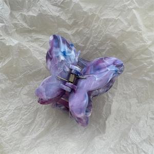 Macro detail of butterfly hair claw with purple marble texture and metal spring