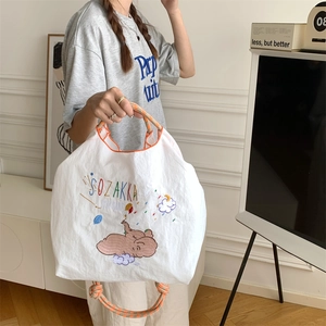 Close-up of cute elephant embroidery and colorful woven rope handles on a white tote bag