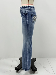Detail showing high waist blue washed jeans with golden star sequin patch on back pocket