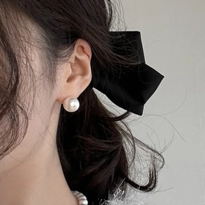 Close-up of large pearl stud earrings with elegant silk bow and matching necklace