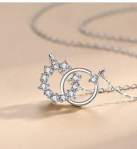 Détail macro du pendentif à deux anneaux entrelacés avec zircons et finition argent
