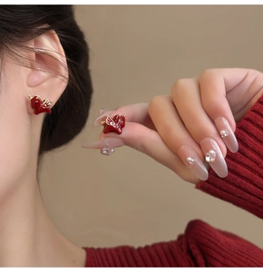 Detail of red enamel dragon earrings with 18k gold plating shown on a model