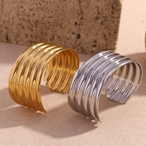 Detailed macro view of gold and silver layered wavy bangles on a textured stone surface