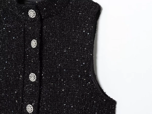Detail der schwarzen Tweed-Weste mit Pailletten-Textur und Kristall-Blumenknöpfen